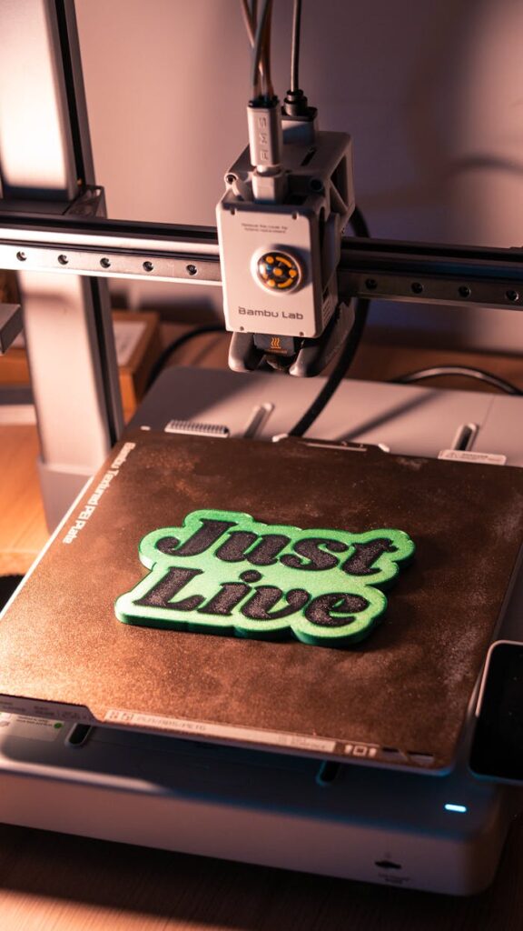 A 3D printer crafting 'Just Live' text in a workshop setting. Ideal for digital technology and innovation themes.